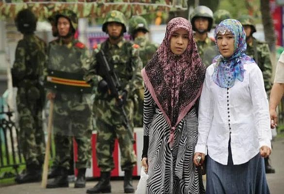 Uyghur women walk warily down a street as they’re watched by Chinese police. Persecution for ethnic and religious reasons is a fact of daily life for the Uyghurs.